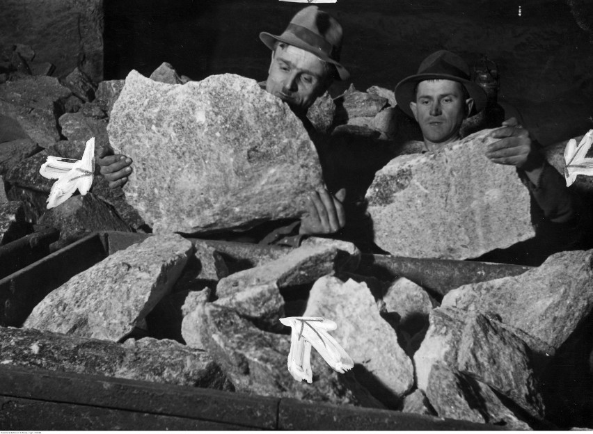 Dwaj górnicy ładują bryły soli na wagonik w kopalni w...