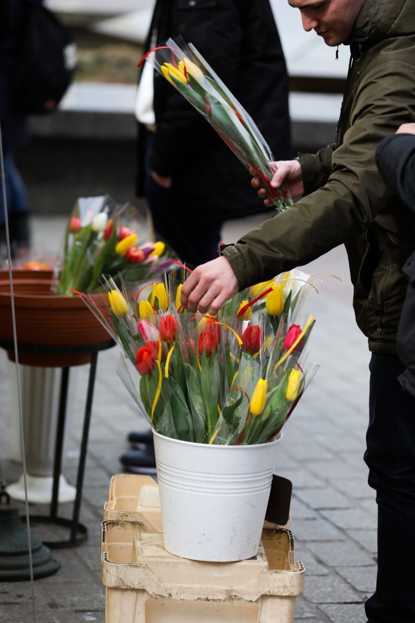 Panowie kupują kwiaty na Dzień Kobiet u kwiaciarek na Rynku