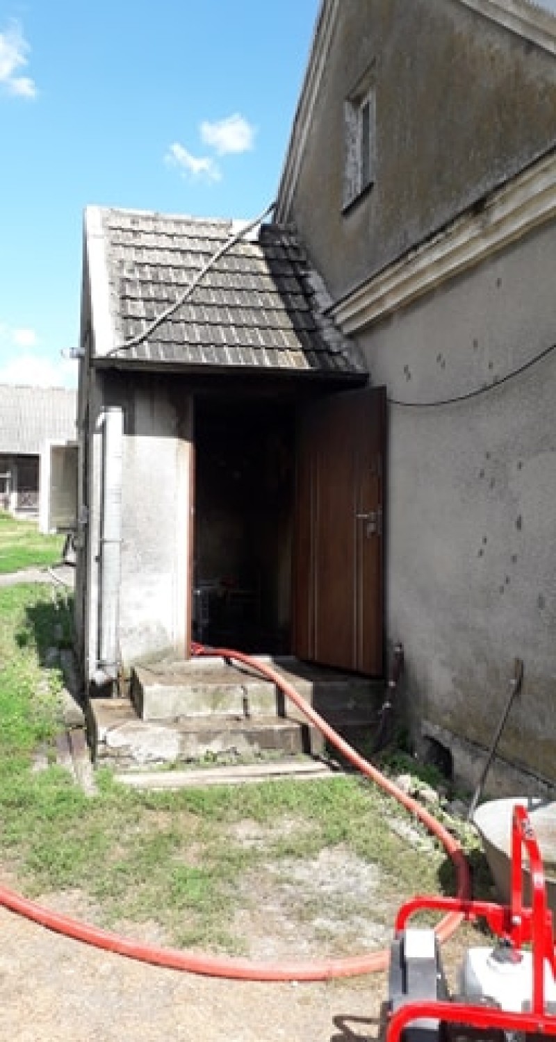 Pożar domu w Ostrówku. Strażacy tłumili płomienie i chłodzili grożącą wybuchem butlę gazową 