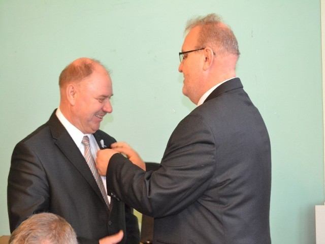 Marek Hojczyk (z prawej) wpina białą wstążkę Stefanowi Skoniecznemu, przewodniczącemu rady
