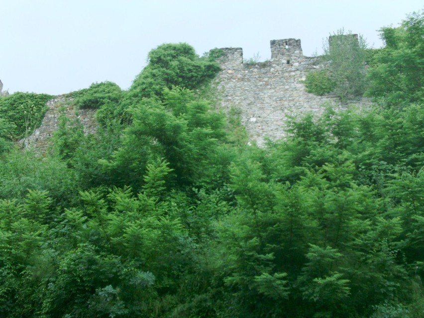 Mury obronne zamku widziane z górzystej drogi do zamku. Fot....