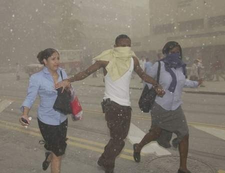 W  chmurach pyłu przechodnie  uciekają z miejsca terrorystycznego zamachu po zawaleniu się wieżowca WTC