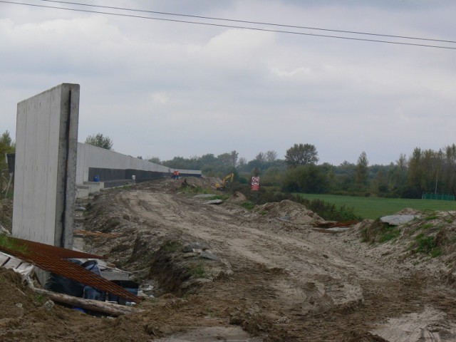 Liczący 2,5 kilometra betonowy mur powstaje wokół osiedla mieszkaniowego i Huty Szkła w prawobrzeżnej części Sandomierza. Rozbudowa wału opaskowego zabezpieczającego przed wodami powodziowymi Hutę Szkła i pobliskie osiedle mieszkaniowe w prawobrzeżnej części Sandomierza, to jeden z ostatnich elementów projektu, który ma uchronić prawobrzeżny  Sandomierz i pobliskie miejscowości przed powtórką powodzi z 2010 roku. Betonowa osłona na wale opaskowym to jeden z kilku elementów dużego projektu "Ochrona przeciwpowodziowa Sandomierza. 
Mur biegnie od Koćmierzowa, gdzie został przerwany wał, aż do mostu na Wiśle w Sandomierzu, gdzie obecnie trwają zintensyfikowane prace.

Na kolejnych slajdach  pokazujemy jak postępują prace przy budowie muru