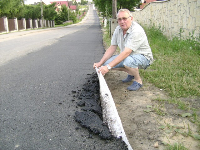 Radny Andrzej Wójcik pokazuje jak łatwo podnieść asfalt z ulicy Podgrabie.