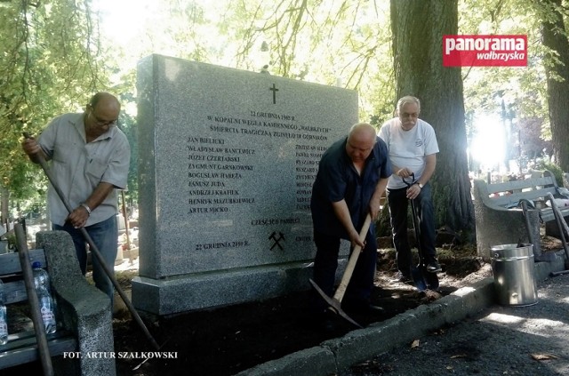 Byli wałbrzyscy górnicy porządkują teren przy tablicy upamiętniającej ich 18 tragicznie zmarłych kolegów