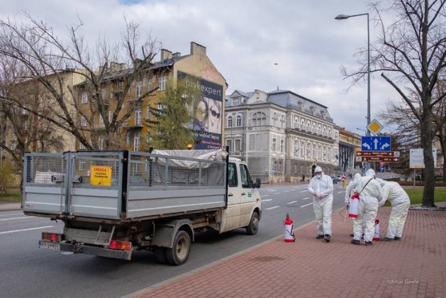 Pracownicy Przedsiębiorstwa Usług Komunalnych ubrani w specjalne kombinezony ochronne i urządzenia do spryskiwania płynem dezynfekującym codziennie przemierzają ulice Tarnowa