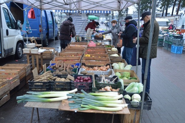 Na placu targowym na straganach pod chmurką jest kolorowo od owoców i warzyw