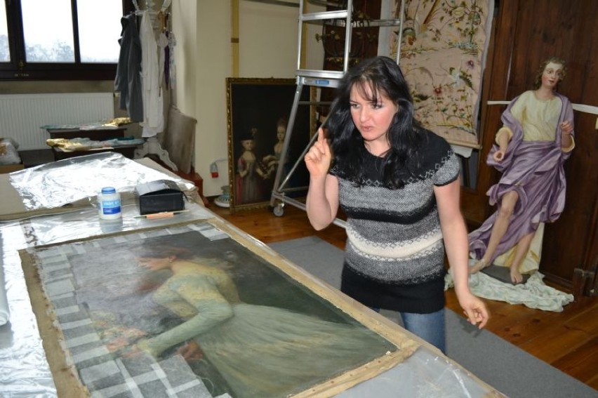 Paulina Drobisz konserwuje jeden z obrazów w pracowni
