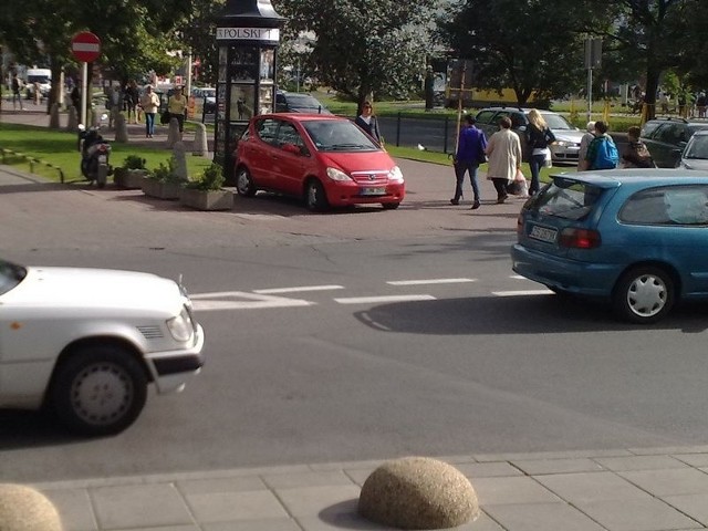 Samochód stoi na środku chodnika.