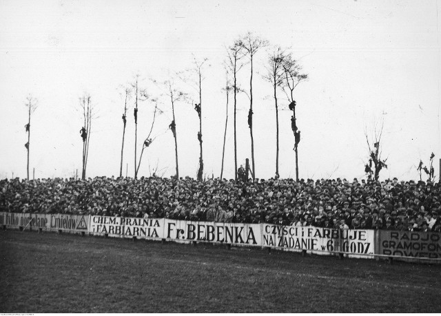 Mecz piłki nożnej Wisła Kraków - Cracovia w Krakowie 1938 r. Tłumy kibiców zgromadzone przed meczem i "zielone trybuny" (kibice) na drzewach. Na ogrodzeniu stadionu widoczna reklama: "Chemiczna pralnia i farbiarnia Fr. Będenka. Czyści i farbuje na żądanie w 6 godzin".