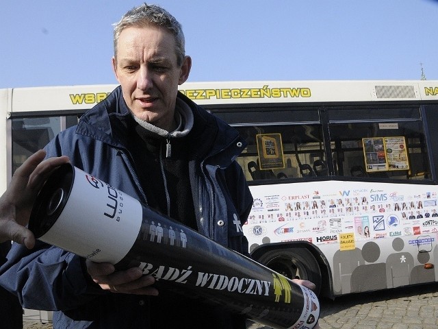 Sławomir Piotrowski z magiczną tubą na tle autobusu użyczonego akcji przez MZK.