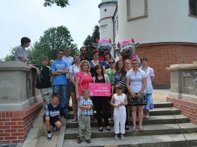 Wychowankowie Domu Dziecka w Skopaniu wychowawcami i symbolicznym czekiem przed zamkiem w Baranowie Sandomierskim