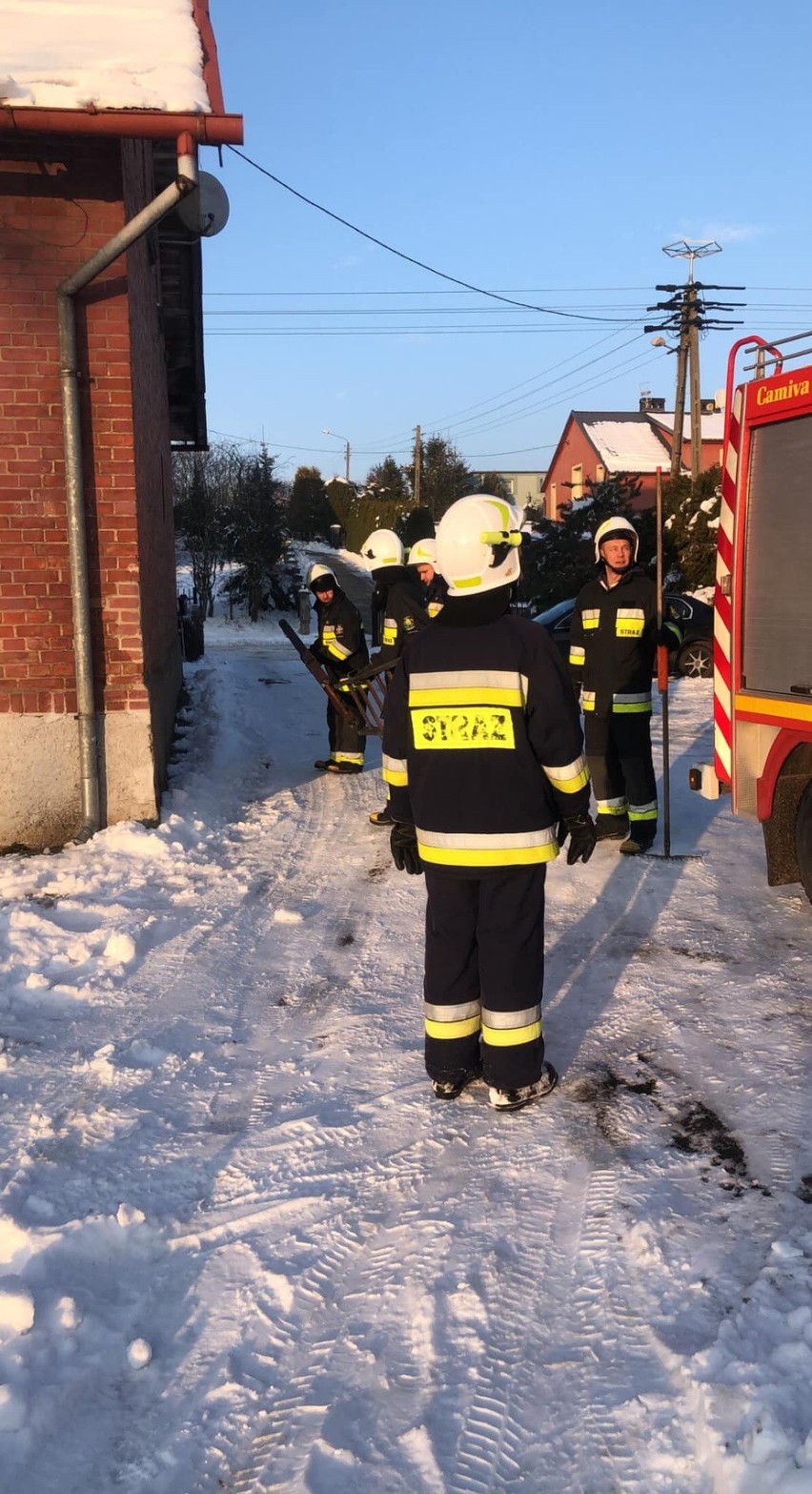 Zwisające sople i zgromadzony na dachu szkoły śnieg w...