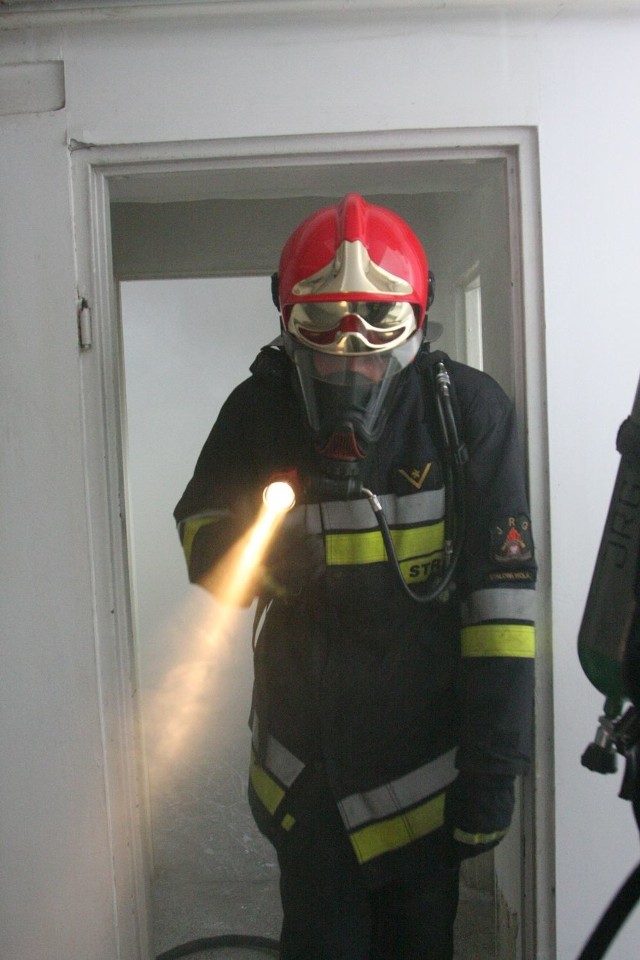Strażak przechodzi przez zadymione pomieszczenie.