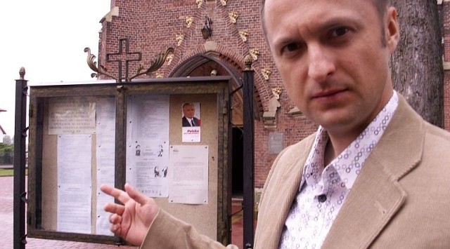 Dariusz Przytuła przy kościelnej tablicy ogłoszeń, na której jest ulotka wyborcza Jarosława Kaczyńskiego.