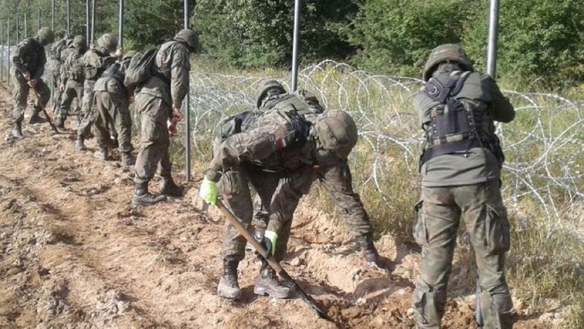 Polscy żołnierze stawiają ogrodzenie z drutu kolczastego na...