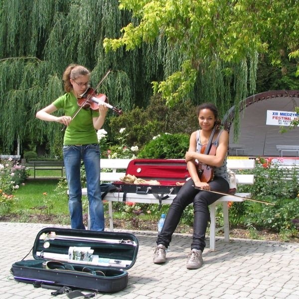 Asia Kraft i Audrey Masiaka, młode skrzypaczki ćwiczą na placu koło fontanny a przy okazji zarabiają.