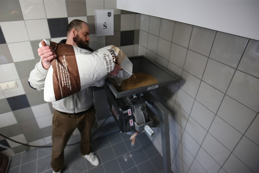 Piwowar Jacek Przywara wsypuje słód do zmielenia. To tzw....