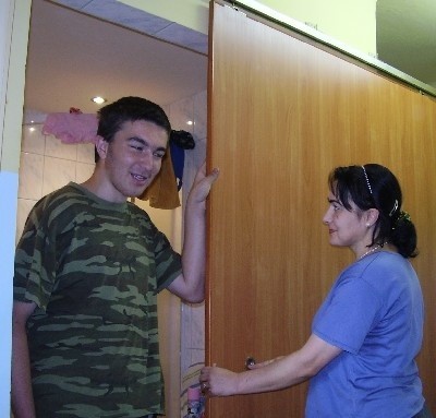 Chingizkhan z mamą Elizą pokazują przesuwane drzwi do własnoręcznie odnowionej łazienki w mieszkaniu, które wynajmują.
