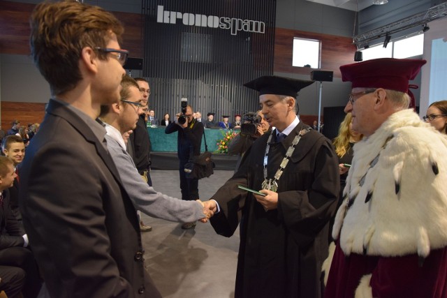 Rektor PK profesor Tadeusz Bohdal (z prawej) i dziekan szczecineckiego wydziału przemysłu drzewnego profesor Dariusz Tomkiewicz wręczają indeksy studentom