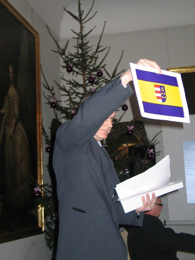 Kazimierz Błasiak, sekretarz starostwa prezentuje wizerunek flagi powiatu.