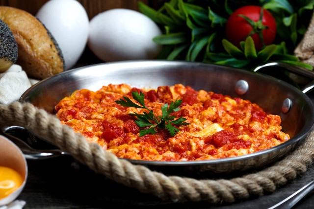 Delikatna jajecznica z pomidorami, cebulą i boczkiem to znakomity pomysł na śniadanie.