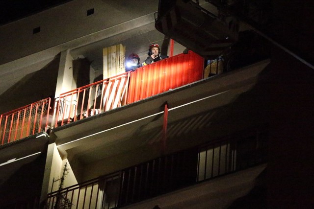 Strażacy na balkonie na ostatnim pietrze wieżowca, gdzie doszło do pożaru od wystrzelonego fajerwerku.