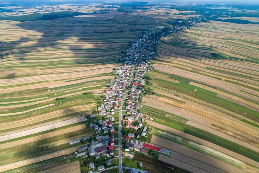 Wąski pas budynków skryty między kilometrami pól – tak...