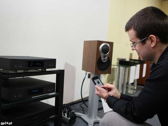 Mariusz Kłujszo steruje urządzeniem do odtwarzania muzyki za pomocą iPhone'a. Sprzęt został wyprodukowany w Szkocji.