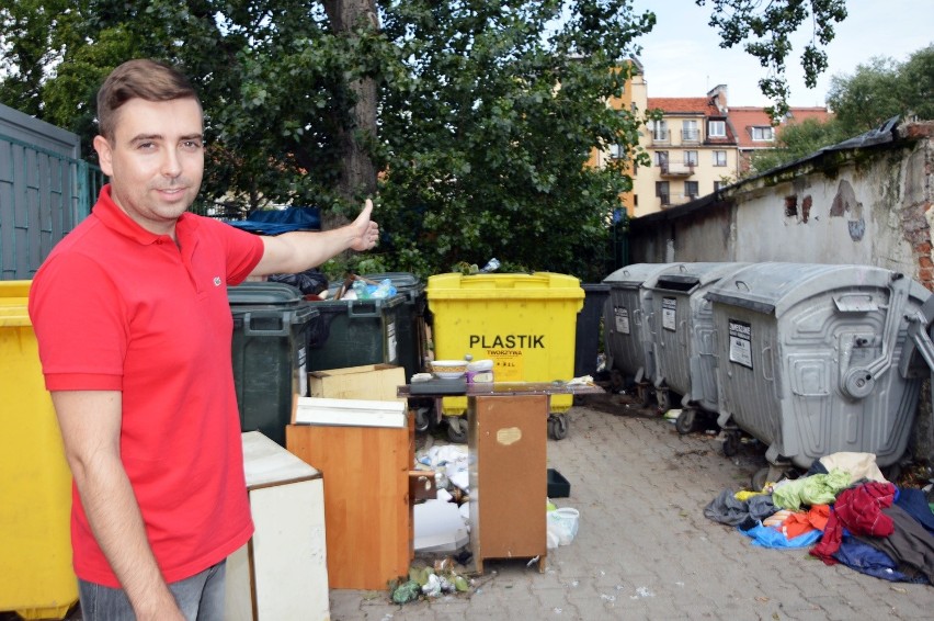 Błażej Szymczak przy śmietnikach na podwórku w kwadracie...