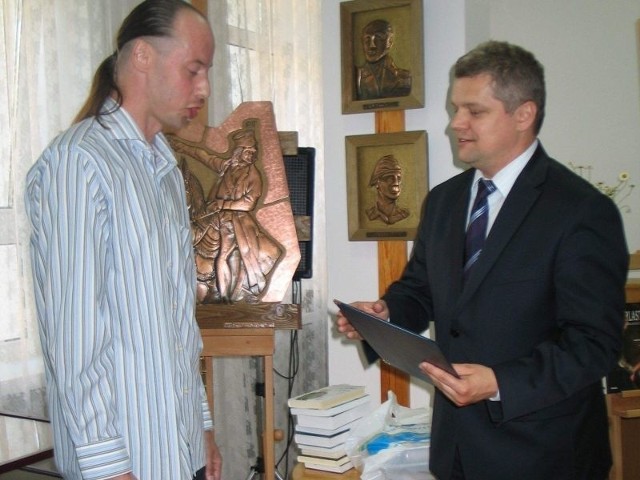 (od lewej) Dawid Bartela, autor zwycięskiej powieści odbiera gratulacje od prezydenta Tarnobrzega, Norberta Mastalerza, który zobowiązał się publicznie, że w chwili wolnego czasu sięgnie po powieść.