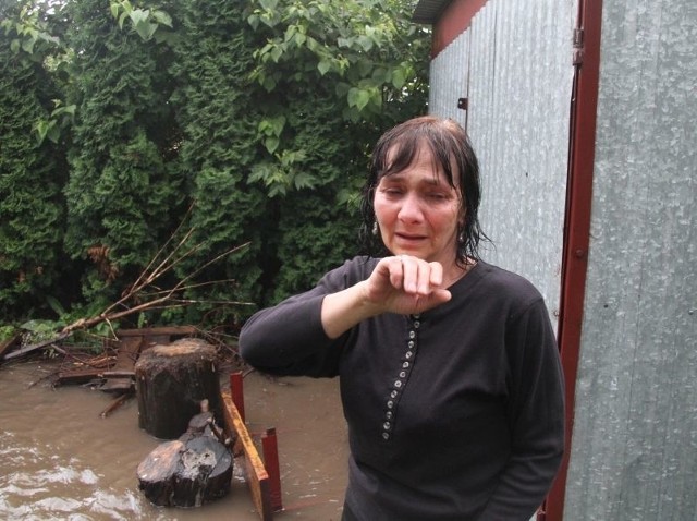 Zapłakana pani Barbara Pagór pokazuje zalane po ulewie podwórko i warzywnik.