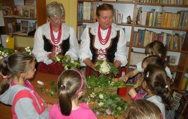 Panie ze Stowarzyszenia "Chata Bogucka" prezentowały dzieciom jak się plecie wianki z polnych kwiatów.