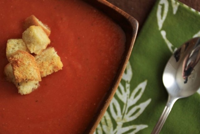Gęstą zupę pomidorową podajemy w miseczkach z grzankami z pszennego chleba.