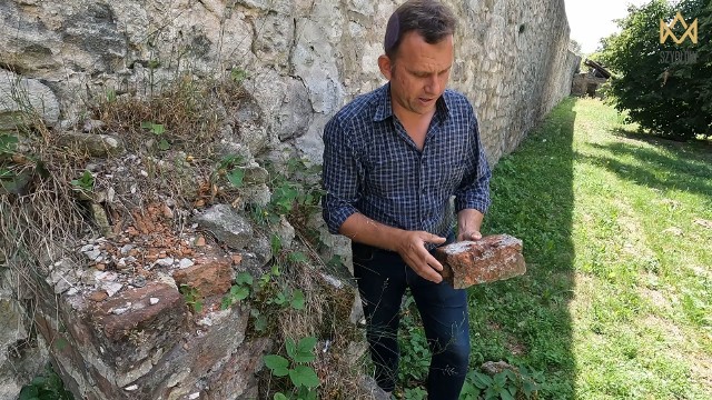 Archeolog Tomasz Olszacki z ponad 600-letnią cegłą