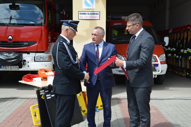 Prezes Ochotniczej Straży Pożarnej w Stalowej Woli brygadier w stanie spoczynku druh Mariusz Janeczko odbiera akt przekazania sprzętu od przewodniczącego Rady Miejskiej w Stalowej Woli Stanisława Sobieraja i ministra Marcina Warchoła.