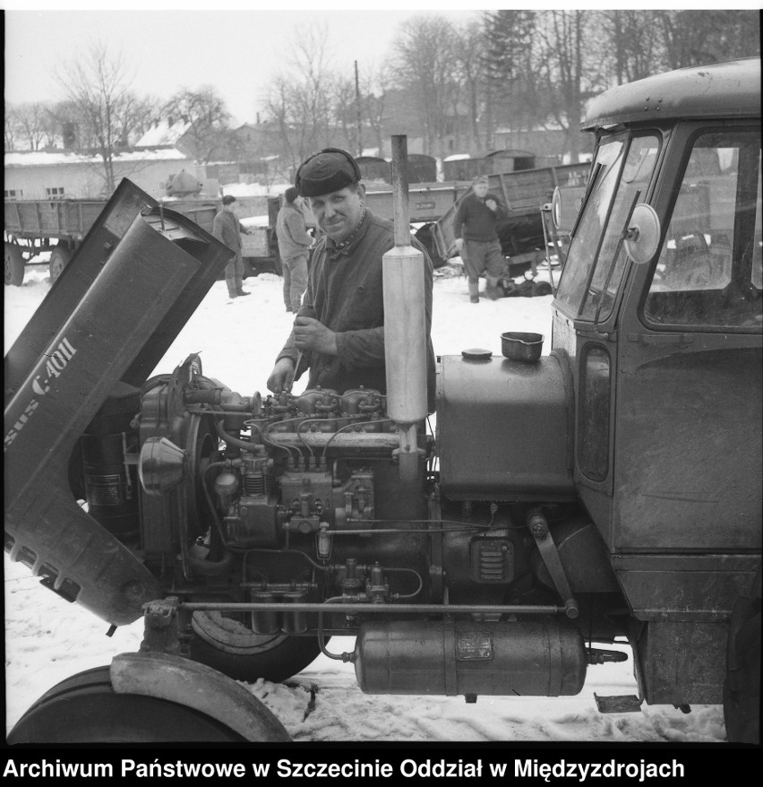 Rolnik naprawiający traktor zima 1969