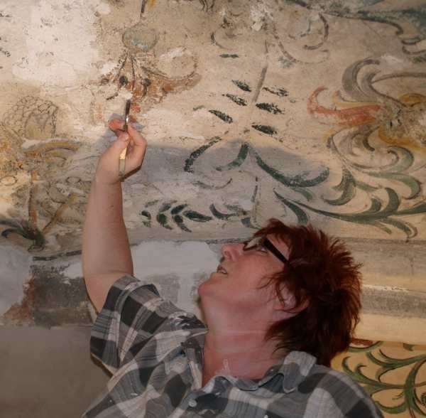 Katarzyna Szymakiewicz pokazuje średniowieczne malowidła, które odkryto podczas prac konserwatorskich w kościele