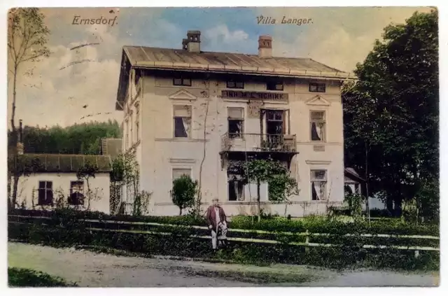 Pocztówka z 1911 r. przedstawiająca "Ernsdorf. Villa Langer"; światłodruk czarno-biały ; willa „Langer” u zbiegu obecnych ul. Zdrojowej i Szkolnej; wydawca: M. L. Schink.
