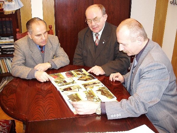 Józef Basta pokazuje zdjęcia zabytków  burmistrzowi Edmundowi Kowalskiemu i  wiceburmistrzowi Jarosławowi Góralowi.