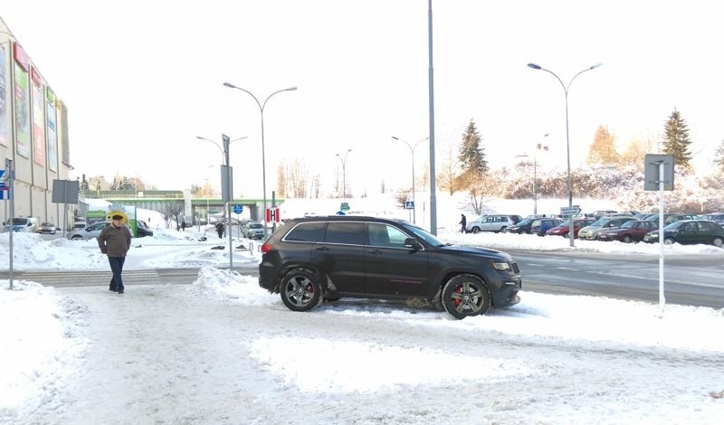 Jeep mimo pustego parkingu stoi na chodniku obok przejścia...
