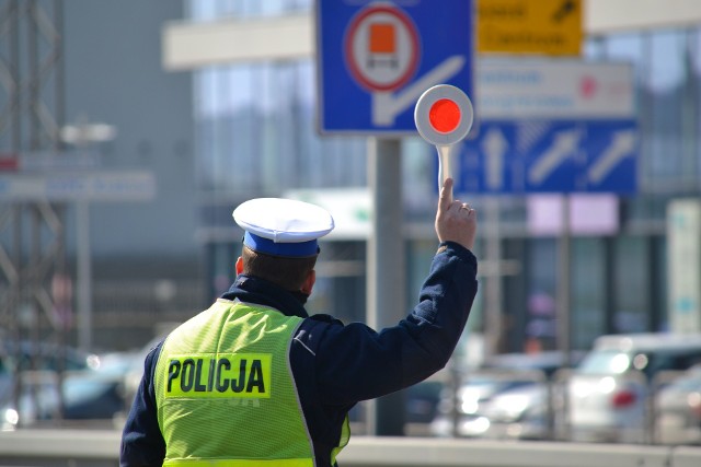 Policjant ruchu drogowego trzyma w ręku tarczę do zatrzymywania pojazdów