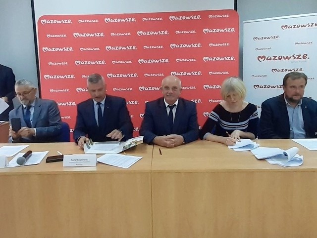 Wicemarszałek Rafał Rajkowski i wójt Rusinowa Andrzej Marian Wesołowski (w środku) podpisują umowę o dotacji dla gminy.