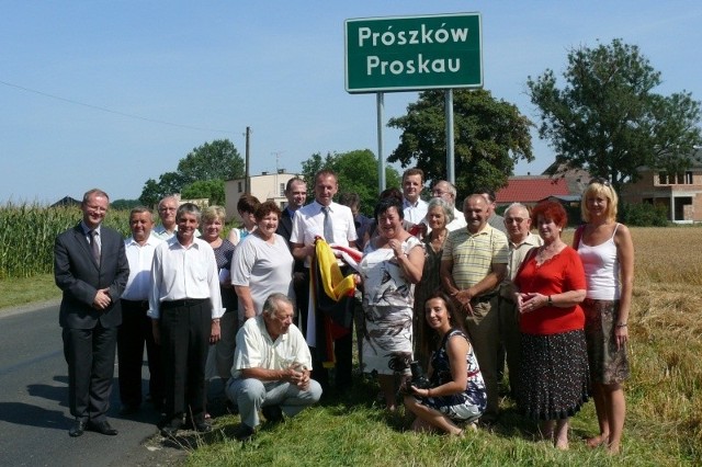 Uczestnicy uroczystości pod tablicą z dwujęzyczną nazwą Prószkowa.