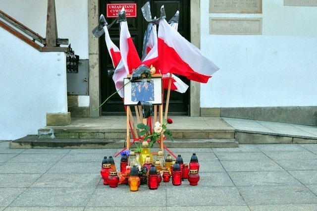 Pod umieszczonym przed ratuszem portretem Pary Prezydenckiej mieszkańcy zapalają znicze i składają kwiaty.