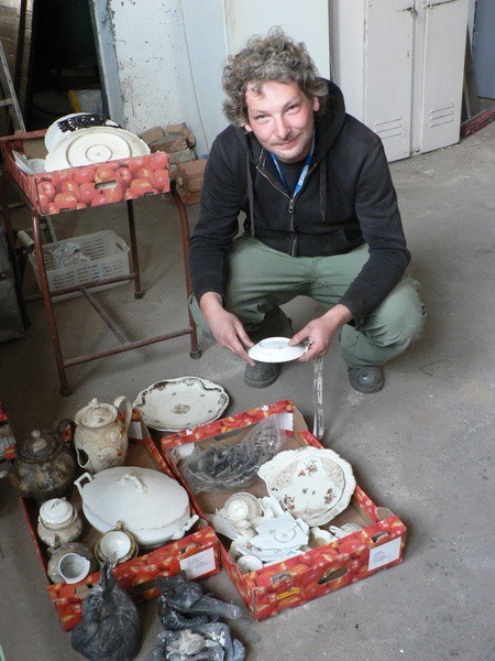 Maciej Marczewski prezentuje zastwę stołową wykopaną podczas badań archeologicznych.