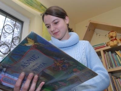 Stażystka Ewa Lach przegląda książkę, którą w ten piątek przeczyta dzieciom zaproszony gość