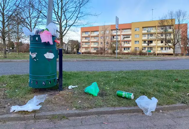 Przepełnione kosze na śmieci przy ul. Wenedów w Koszalinie. Wiatr roznosi nieczystości po okolicznych trawnikach i chodnikach.