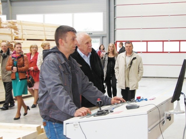 - Przy swojej maszynie tnę i frezuję drewniane belki, z których powstają panele modułowe - mówi pracownik firmy Nordhus Artur Paszkowski (na pierwszym planie)