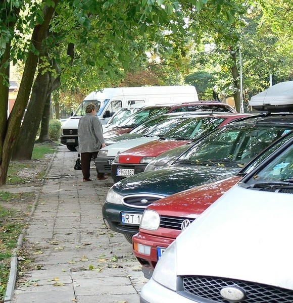 Przejście chodnikiem przy ulicy Słowackiego jest mocno utrudnione przez zaparkowane na trakcie samo-chody.